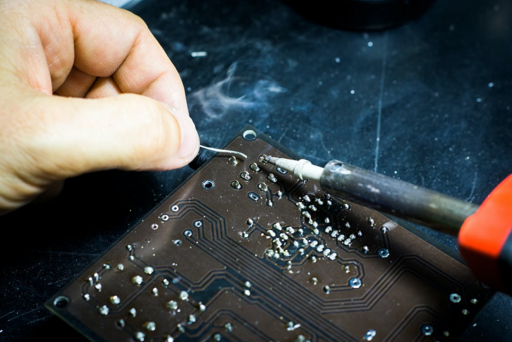 A person is soldering wires over a PCB